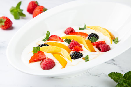 raspberry, peach, strawberry, black berry, strawberry and mint in whipped cream, side viewの写真素材