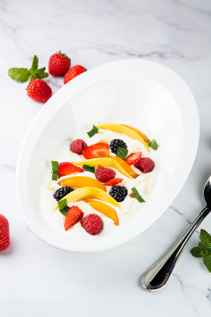 raspberry, peach, strawberry, black berry, strawberry and mint in whipped cream, side viewの写真素材