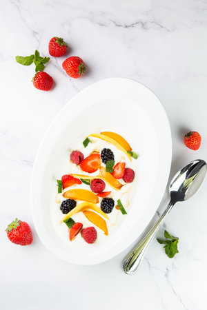 raspberry, peach, strawberry, black berry, strawberry and mint in whipped cream, side viewの写真素材