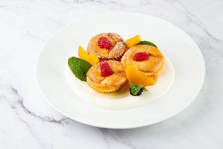 muffins with peach, raspberry, black berry and mint covered with powdered sugar, side viewの写真素材