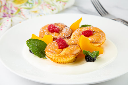 muffins with peach, raspberry, black berry and mint covered with powdered sugar, side viewの写真素材