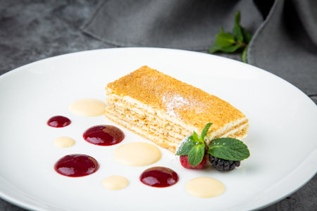 white sponge cake with drops of syrup, mint and wild berries on a round plate side veiwの写真素材