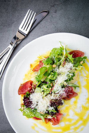 side view of salad with red fish, herbs and cheese on a white plateの写真素材