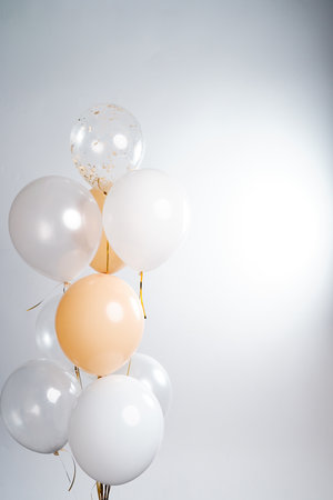 Balloons in white, beige and transparent colors on a gray background.の写真素材