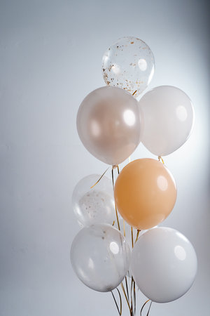 Balloons in white, beige and transparent colors on a gray background.の写真素材