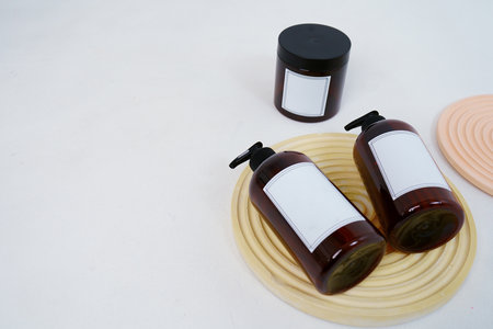 Body care. two bottles with a dispenser and a jar of body cream on a geometric stand on a light gray...