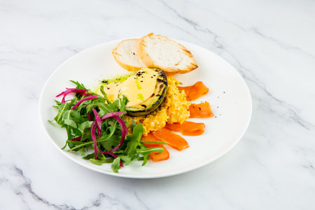 a mix of salmon, arugula salad, white bread and baked avocado with cheese side viewの写真素材
