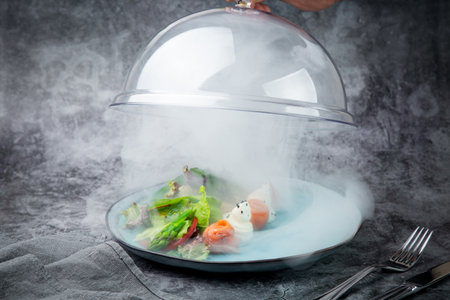 salad of leaves of different types of lettuce and fish rolls under a glass coverの写真素材