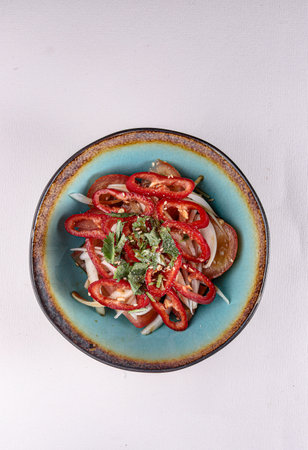 red sweet pepper with onions, tomatoes and vegetables in a plate on a white background, top viewの写真素材