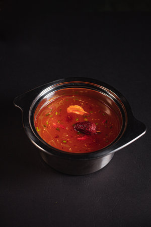 soup broth in an iron plate on a dark background side viewの写真素材