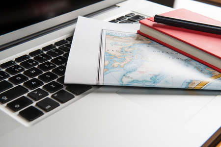 Color photograph of a laptop on which there is a map, a notebook and a pen.の写真素材
