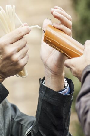 Detail of some hands with a wick lighting the candle of a penitent of the brotherhood ofの写真素材