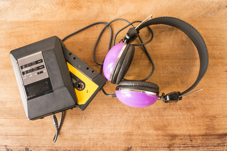 Personal stereo with a cassette tape inside and headphones on a worn wooden boardの写真素材