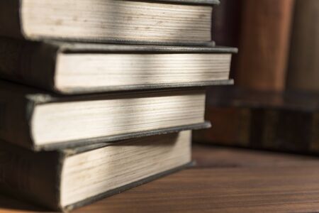 Detail photograph of an old books in which the texture of the leaves is appreciated with a stack of books in the background.の写真素材