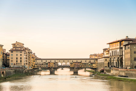 View of the Ponte Vecchio over the Arno River as it passes through Florence, with a clear sky in the background at sunsetのeditorial素材