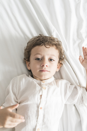 Child lying on the bed playing and gesturing.の写真素材