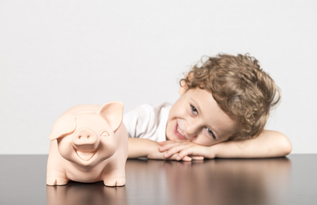Child next to piggy bank on white background.の写真素材