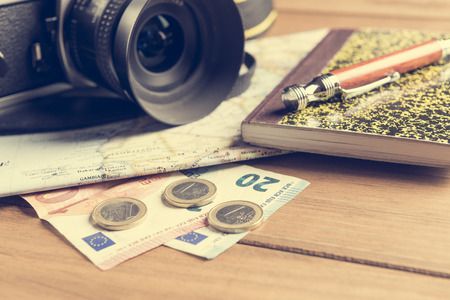 Travel concept. Camera, map, notebook, ball pen and money on wooden tableの写真素材