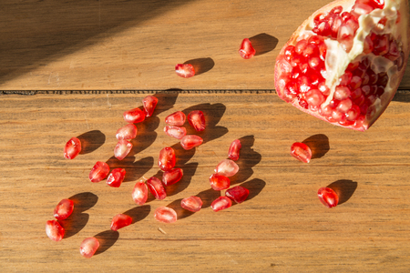 Healthy food concept. Still life with a pomegranates with some grains on wooden table.の写真素材