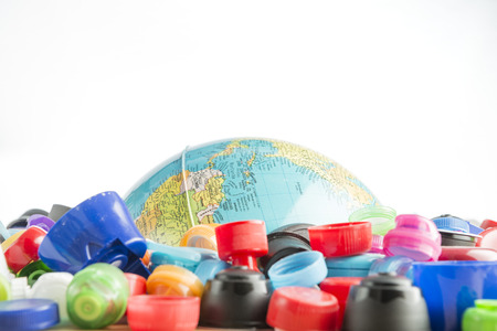 Conceptual and metaphorical photograph of a globe buried in plastic stoppers.