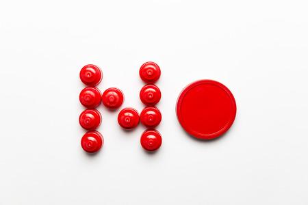 Conceptual photo of red plastic stoppers forming the word NO, on a white background.