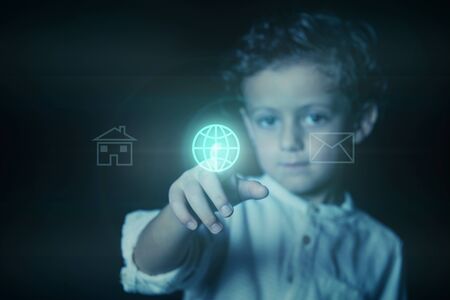 Child pressing the button, illuminated in blue, with the world wide web icon on a virtual screen. Photograph showing the concept of the use of technology and internet by children.の写真素材