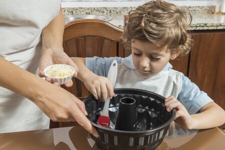A woman and a child spreading a cake tin with butter. Concepts of maternity and family.の写真素材