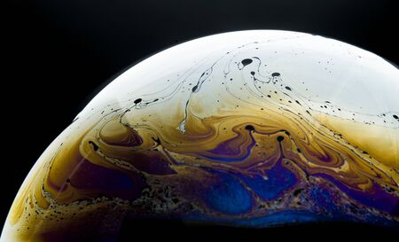 Colors and shapes created the surface of a soap bubble on black background.