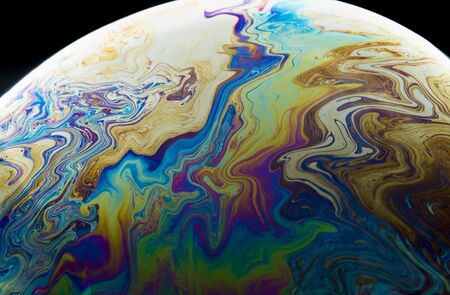 Colors and shapes created the surface of a soap bubble on black background.の写真素材