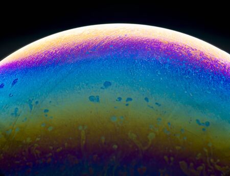 Colors and shapes created the surface of a soap bubble on black background.の写真素材