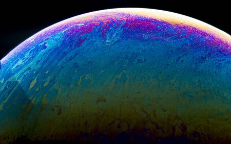 Colors and shapes created the surface of a soap bubble on black background.