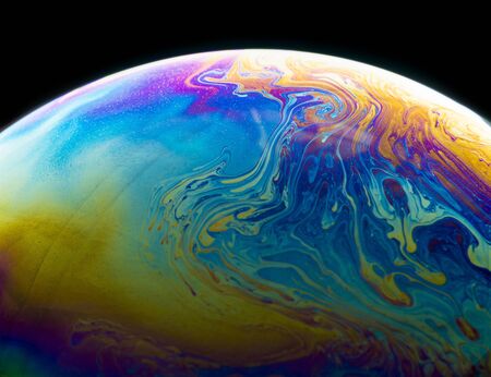 Colors and shapes created the surface of a soap bubble on black background.