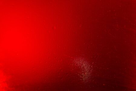 Texture created in a glass with water drops on red background.