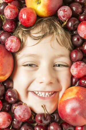 Creative portrait of a boy with his face surrounded by fruits.