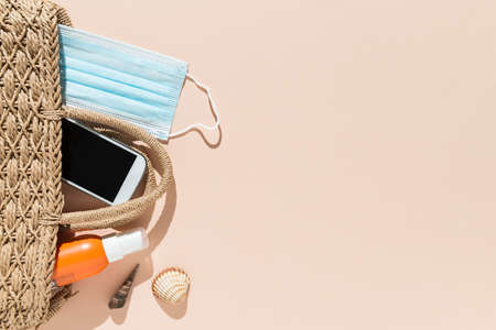 Top view of beach objects, face mask and hydro alcoholic gel on pink background. Summer and vacation...