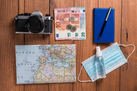 Conceptual still life with various objects related to travel and mask, on wooden boards. Travel...