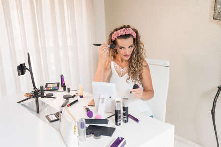 Young female vlogger recording a make-up video for her vlog. Influencer marketing in social media...