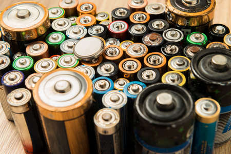 Flat batteries placed neatly on a wooden table. Concept of recycling and care for the environment.の写真素材
