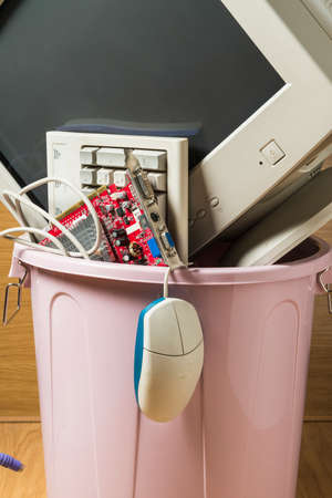 Computer and obsolete technological objects in a rubbish bin. Concept of technological waste and its recycling.の写真素材