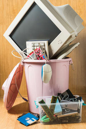 Computer and obsolete technological objects in a rubbish bin. Concept of technological waste and its...