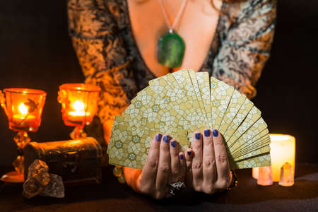 Detail of a woman's hands showing a deck of tarot cards. Concept of a divination session with tarot cards.の写真素材