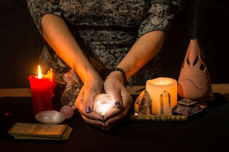 Detail of a woman's hands with a crystal ball to look into the future. Concept of a divination session with a crystal ball.の写真素材