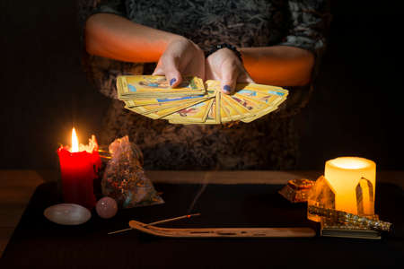 Detail of a woman's hands cleaning tarot cards with incense smoke during a divination session. Concept of a divination session with tarot cards.の写真素材