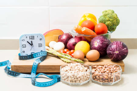 Still life with a clock, a tape measure and healthy food. Conceptual image of intermittent fasting, a diet with benefits such as the regenerative mechanism of autophagy.の写真素材