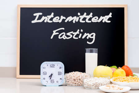 Still life with healthy food, a clock and a blackboard. Copy space. Conceptual photograph about intermittent fasting, a diet that brings benefits such as the regeneration mechanism of autophagy.の写真素材