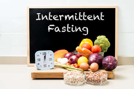 Still life with healthy food, a clock and a blackboard with space for copying. Conceptual image of intermittent fasting, a diet with benefits such as the regenerative mechanism of autophagy.の写真素材