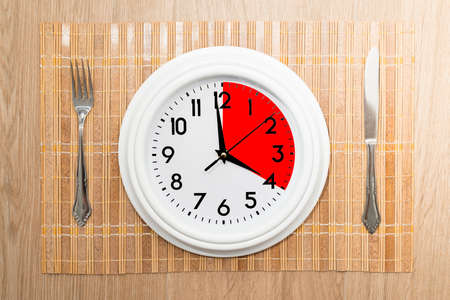 Circular clock with one portion marked in red. Concept of intermittent fasting, a diet that provides benefits such as the regenerative mechanism of autophagy.の写真素材