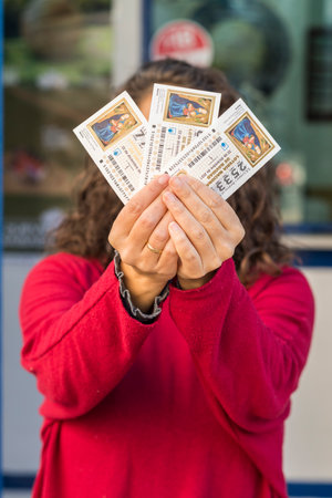 Arahal. Seville. Spain. 27 November 2021. A woman at the entrance of a lottery administration shows some lottery tickets for the traditional Christmas lottery draw in Spain held every year on 22 December.のeditorial素材