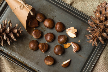 Paper cone with chestnuts on a black metal tray and a brown hessian cloth.の写真素材