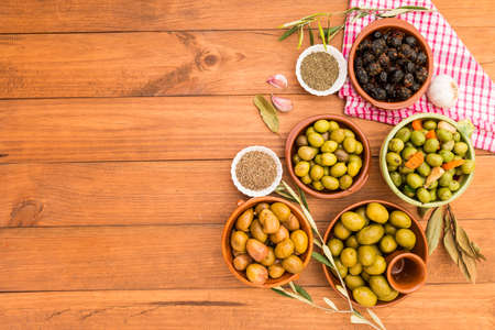 Still life with different varieties of olives, presented in bowls on wooden boards, seasoned with different traditional dressings. Traditional homemade dressings, typical of Mediterranean cuisine.の写真素材